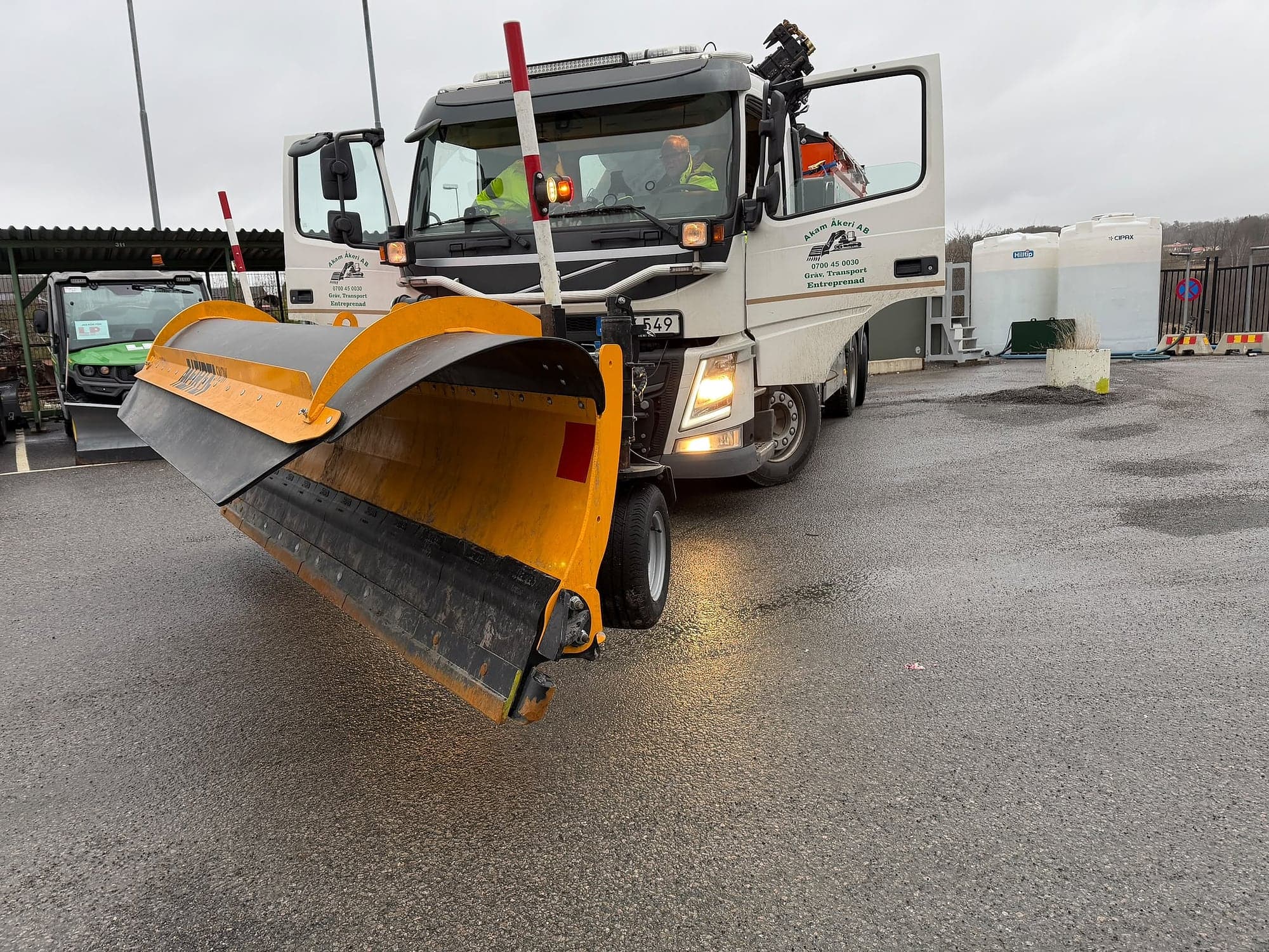 Lastbil med ett gult plogblad monterat framtill.